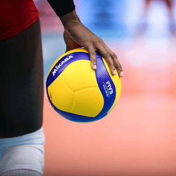 Žoge za odbojko v roki igralca s pisanjem barvne kombinacije in oznako FIVB.