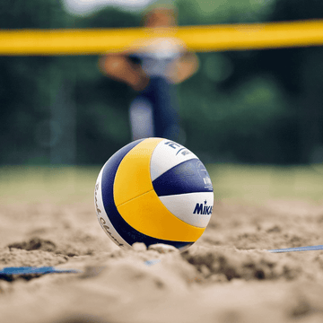 Žoge in dodatki za odbojko na plaži, s poudarkom na žogi, pripravljeni za trening ali tekmo.